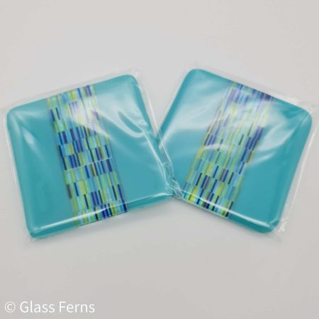A pair of fused glass tapestry stripe coaster with turquoise edging