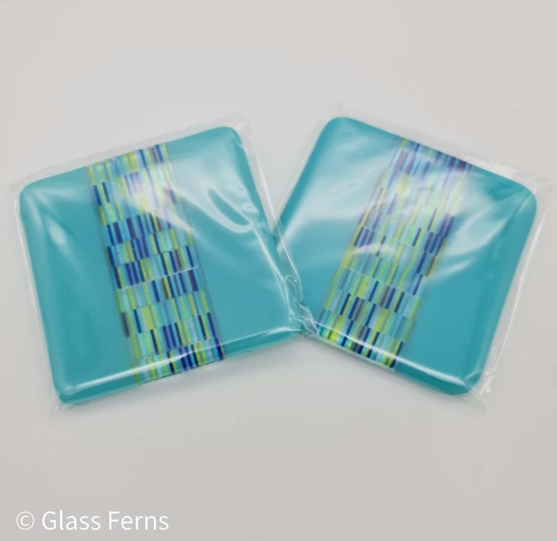 A pair of fused glass tapestry stripe coaster with turquoise edging