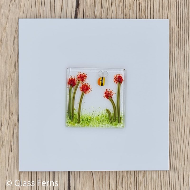 Keepsake fused glass blank card featuring a little buzzing bee in amongst bright red pom-pom flowers