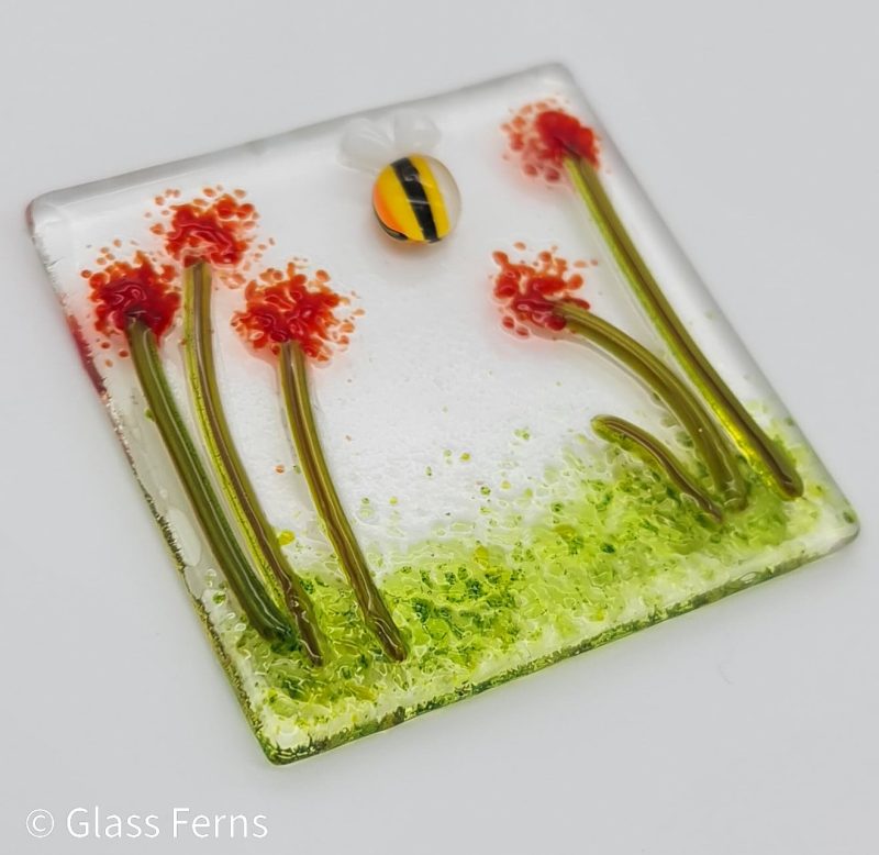 Keepsake fused glass blank card featuring a little buzzing bee in amongst bright red pom-pom flowers