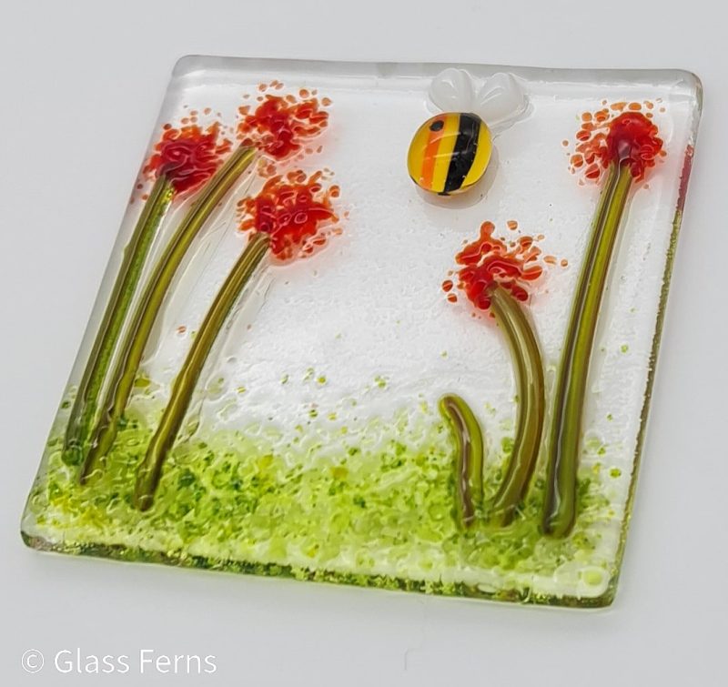 Keepsake fused glass blank card featuring a little buzzing bee in amongst bright red pom-pom flowers