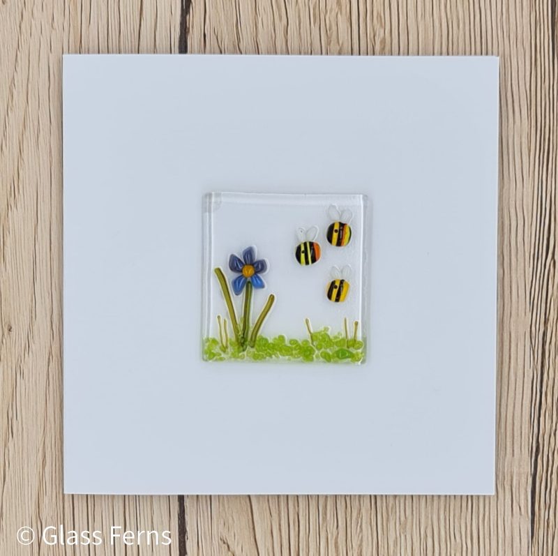 Keepsake fused glass blank card featuring a trio of bees buzzing by a cute purple and blue flower