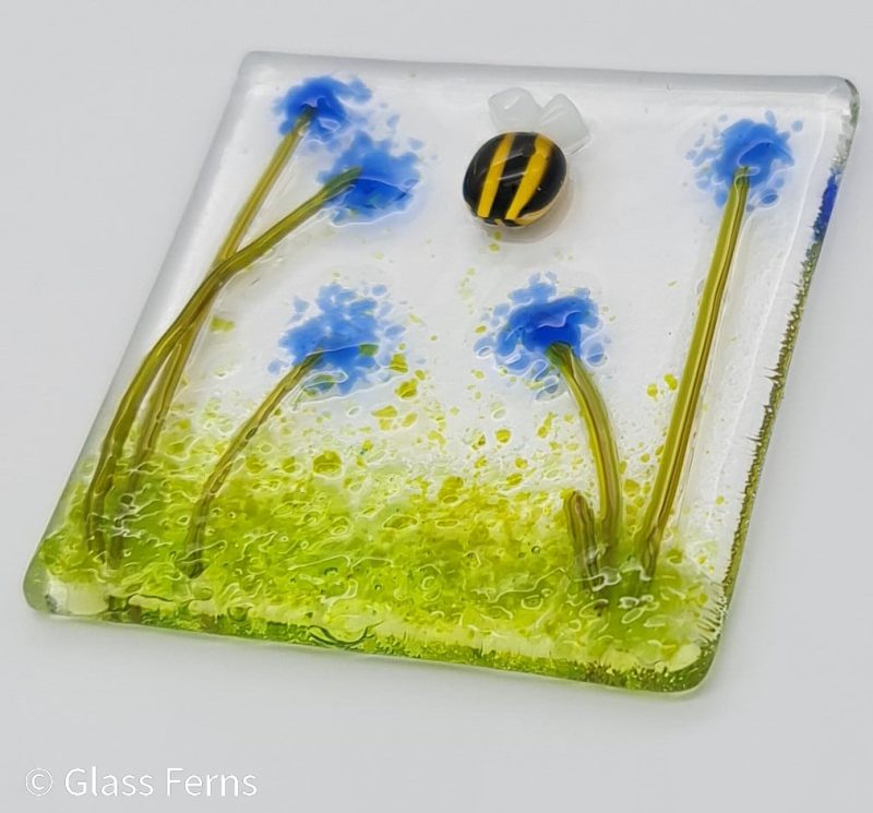 Keepsake fused glass blank card featuring a little bee buzzing in amongst blue pom-pom flowers