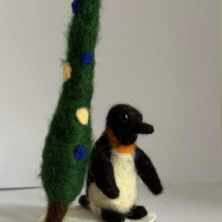 Needle felted Igloo the penguin by a pine tree 🌲