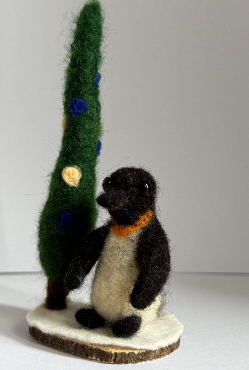Needle felted Igloo the penguin by a pine tree 🌲