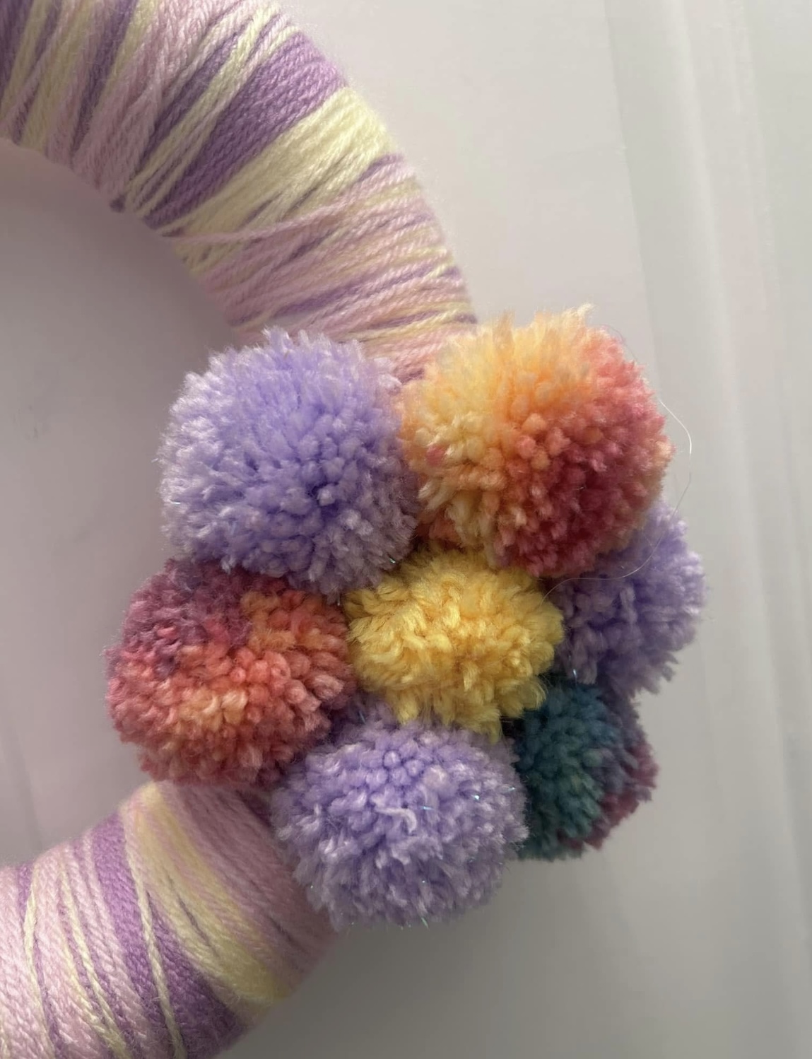 Handmade lilac, lemon and pink wool wrapped wreath with pompom flower