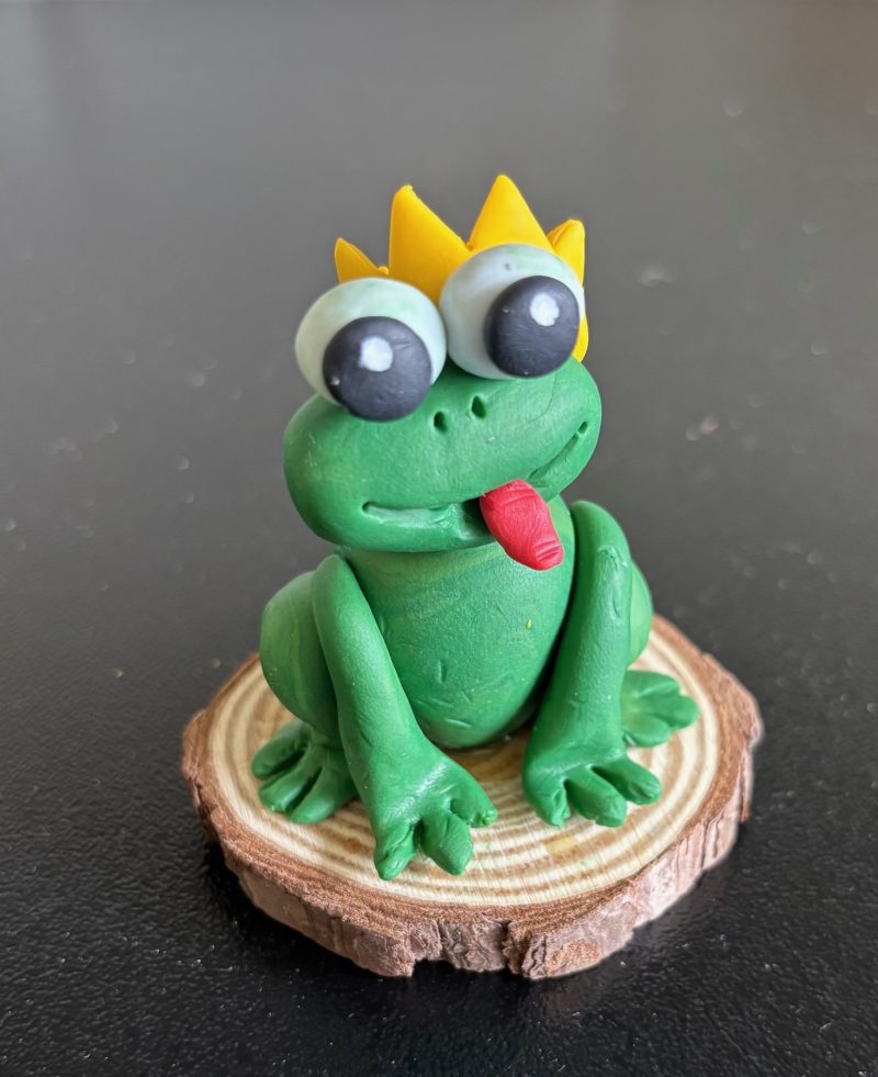 Handmade Clay Green frog sitting on a Wooden Slice