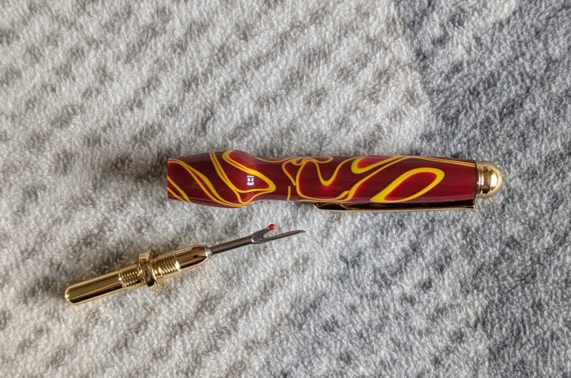 Seam ripper-unpicker made from red and yellow acrylic with gold coloured fittings