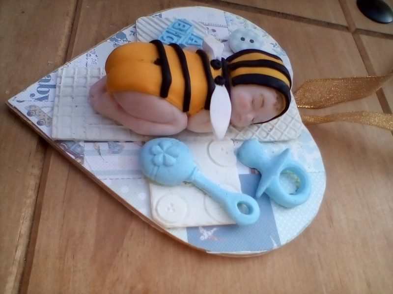 wooden plaque with clay bee baby figure