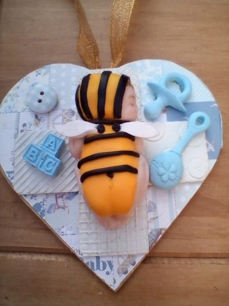 wooden plaque with clay bee baby figure