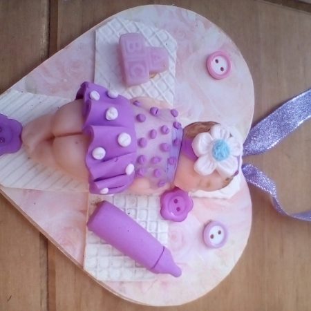 wooden plaque with clay baby figure