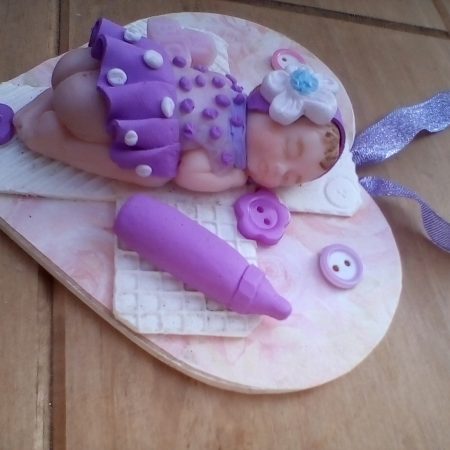 wooden plaque with clay baby figure