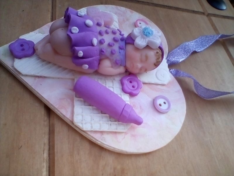 wooden plaque with clay baby figure