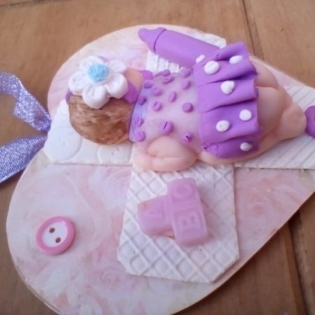 wooden plaque with clay baby figure