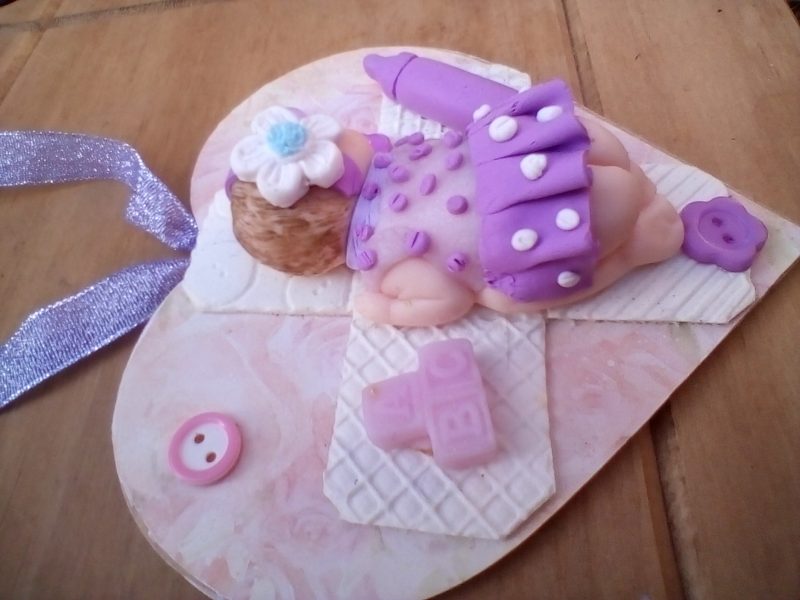 wooden plaque with clay baby figure