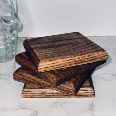 4 Handmade square oak coasters stacked on a marble side and white background