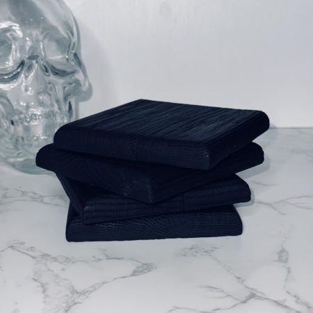 4 Charred oak coasters stacked on a marble side and white background