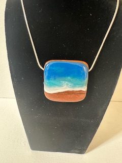 Hand made ocean wave pendant on wood