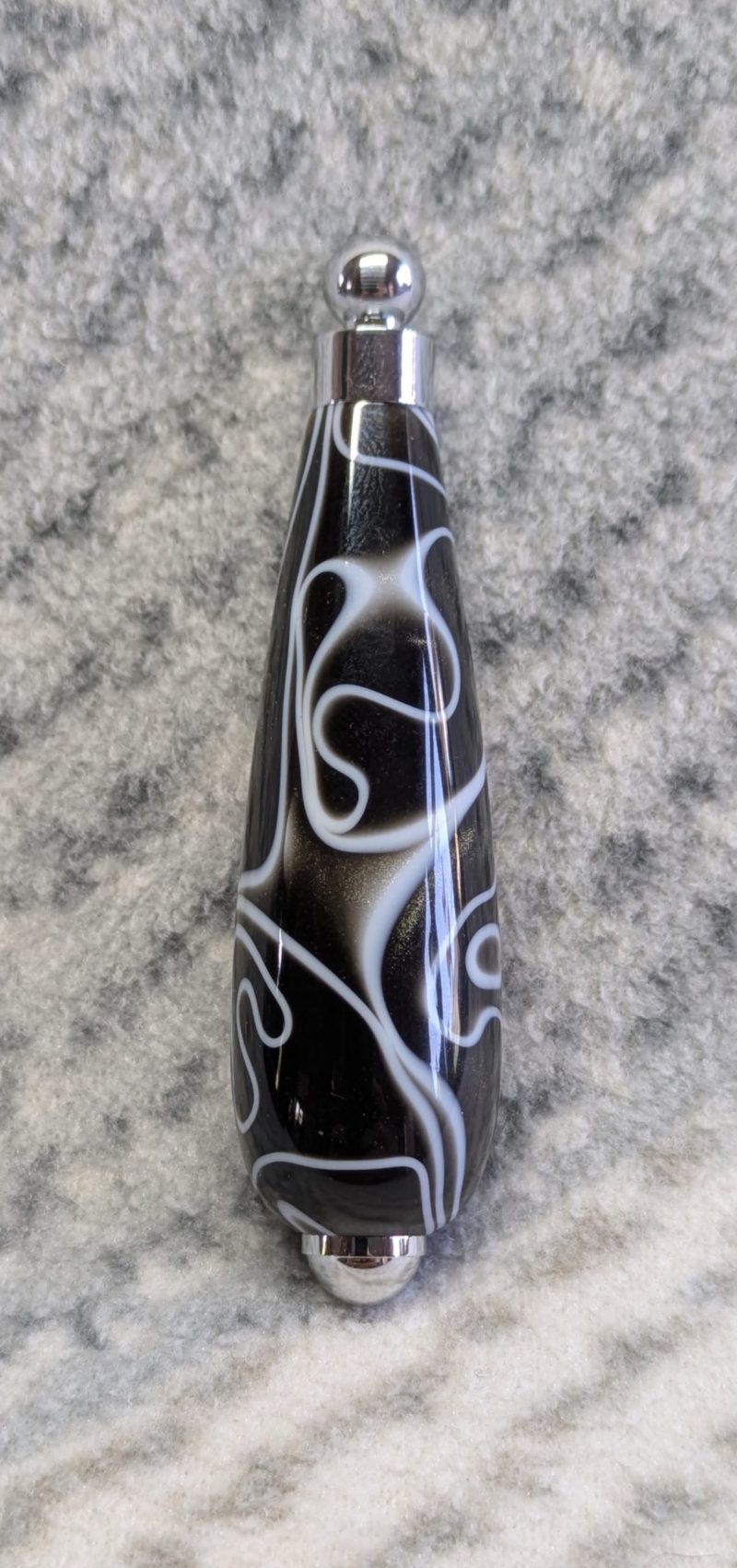 Light switch pull pendant made from black acrylic with white swirls and chrome fittings