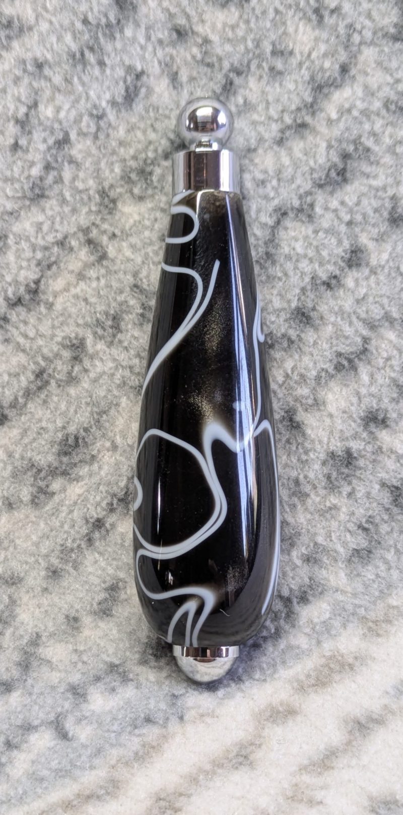 Light switch pull pendant made from black acrylic with white swirls and chrome fittings
