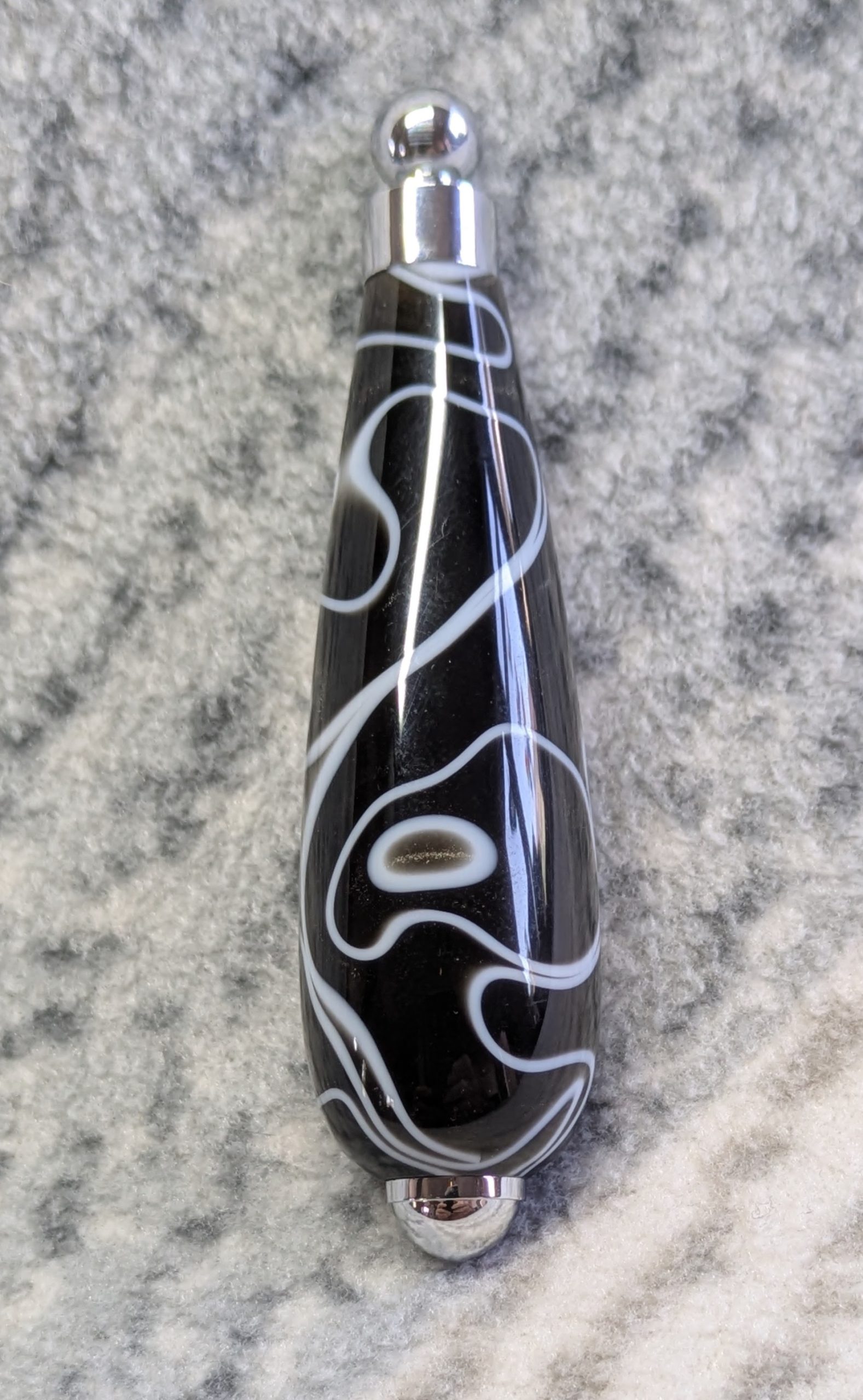 Light switch pull pendant made from black acrylic with white swirls and chrome fittings