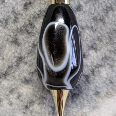 Light switch pull pendant made from black acrylic with white swirls and gold coloured fittings