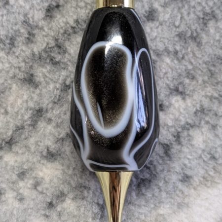 Light switch pull pendant made from black acrylic with white swirls and gold coloured fittings