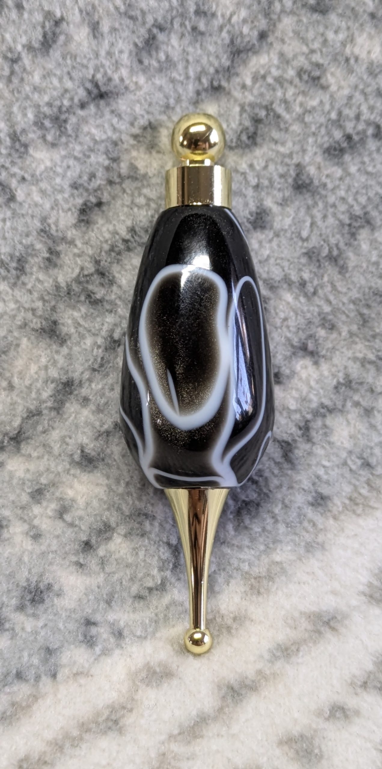 Light switch pull pendant made from black acrylic with white swirls and gold coloured fittings