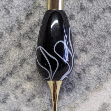 Light switch pull pendant made from black acrylic with white swirls and gold coloured fittings