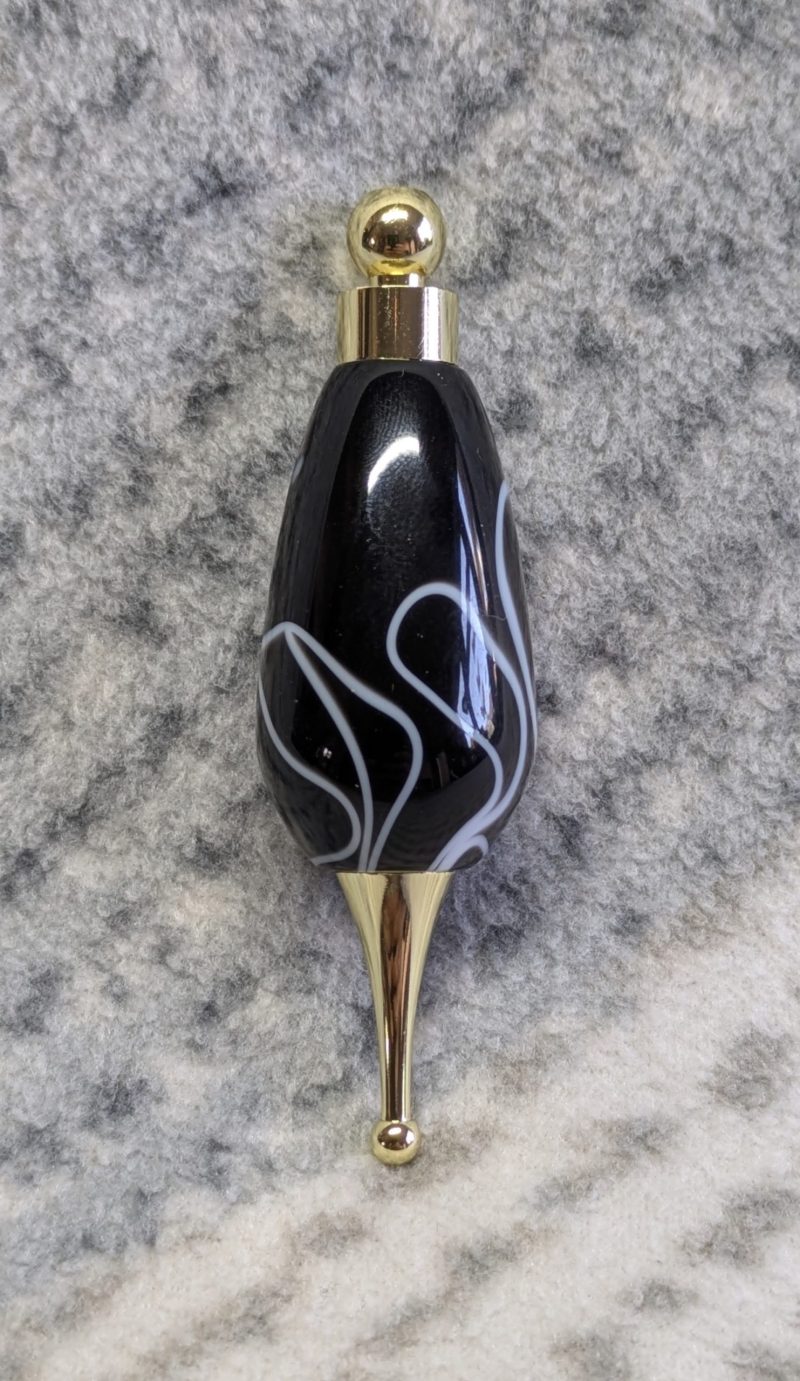 Light switch pull pendant made from black acrylic with white swirls and gold coloured fittings