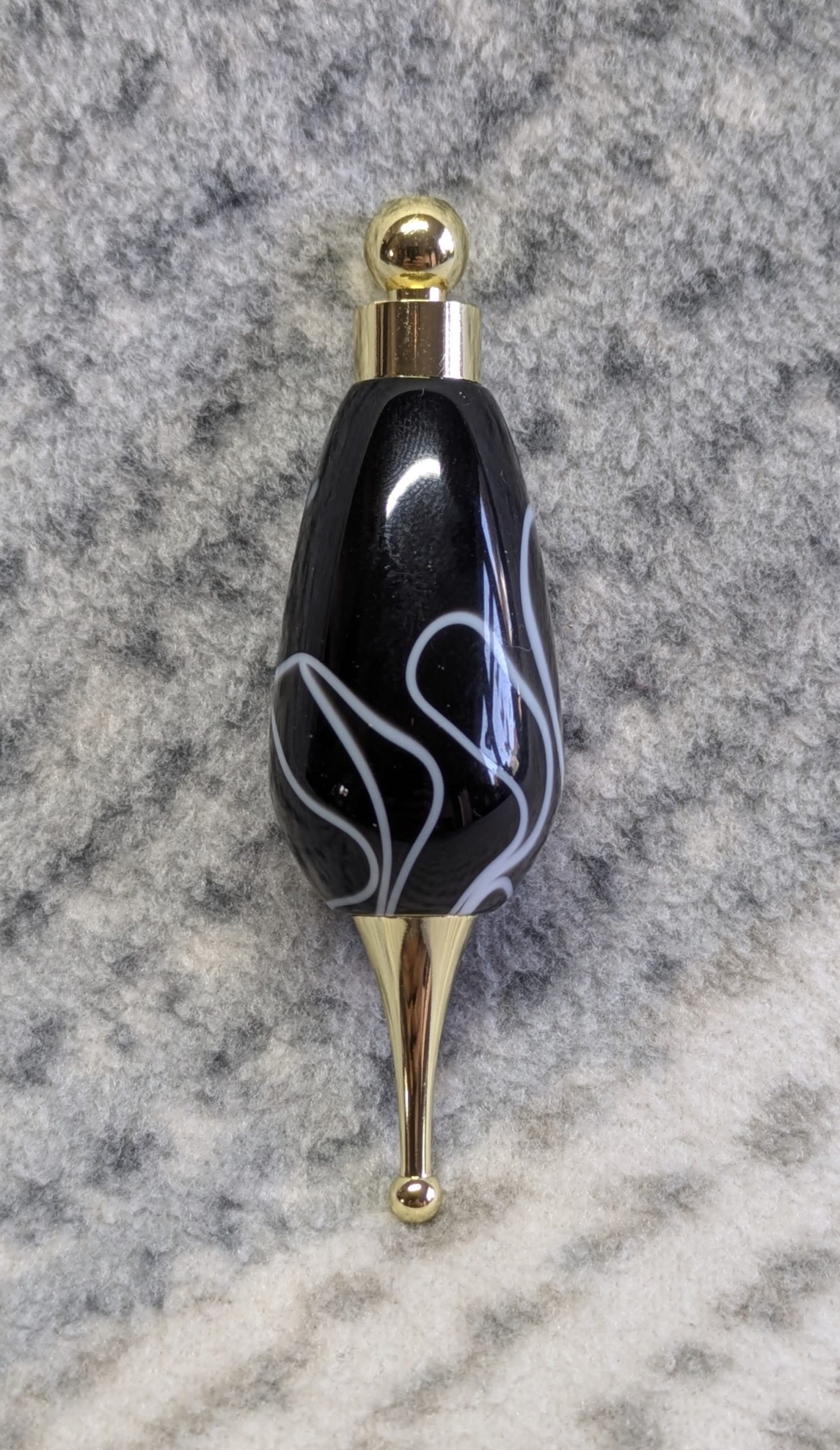 Light switch pull pendant made from black acrylic with white swirls and gold coloured fittings
