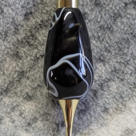 Light switch pull pendant made from black acrylic with white swirls and gold coloured fittings