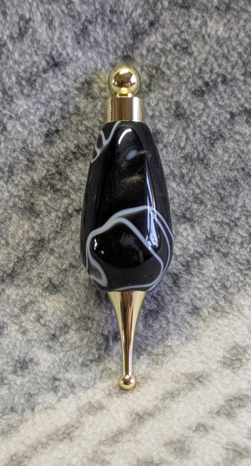Light switch pull pendant made from black acrylic with white swirls and gold coloured fittings