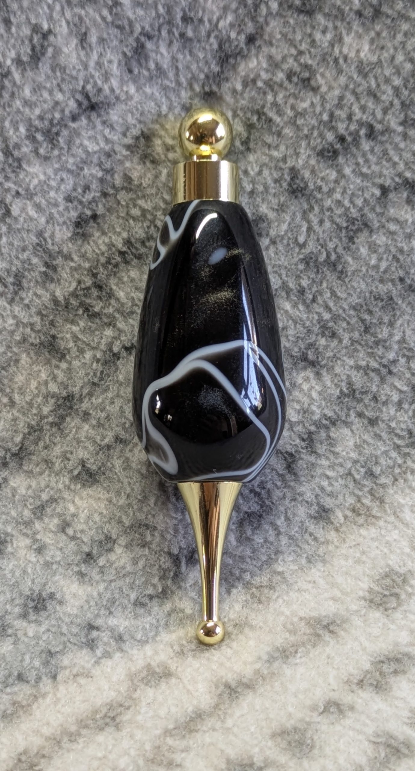 Light switch pull pendant made from black acrylic with white swirls and gold coloured fittings