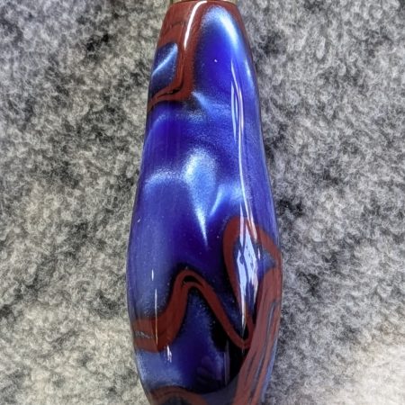 Light switch pull pendant made from blue acrylic with red swirls and gold coloured fittings