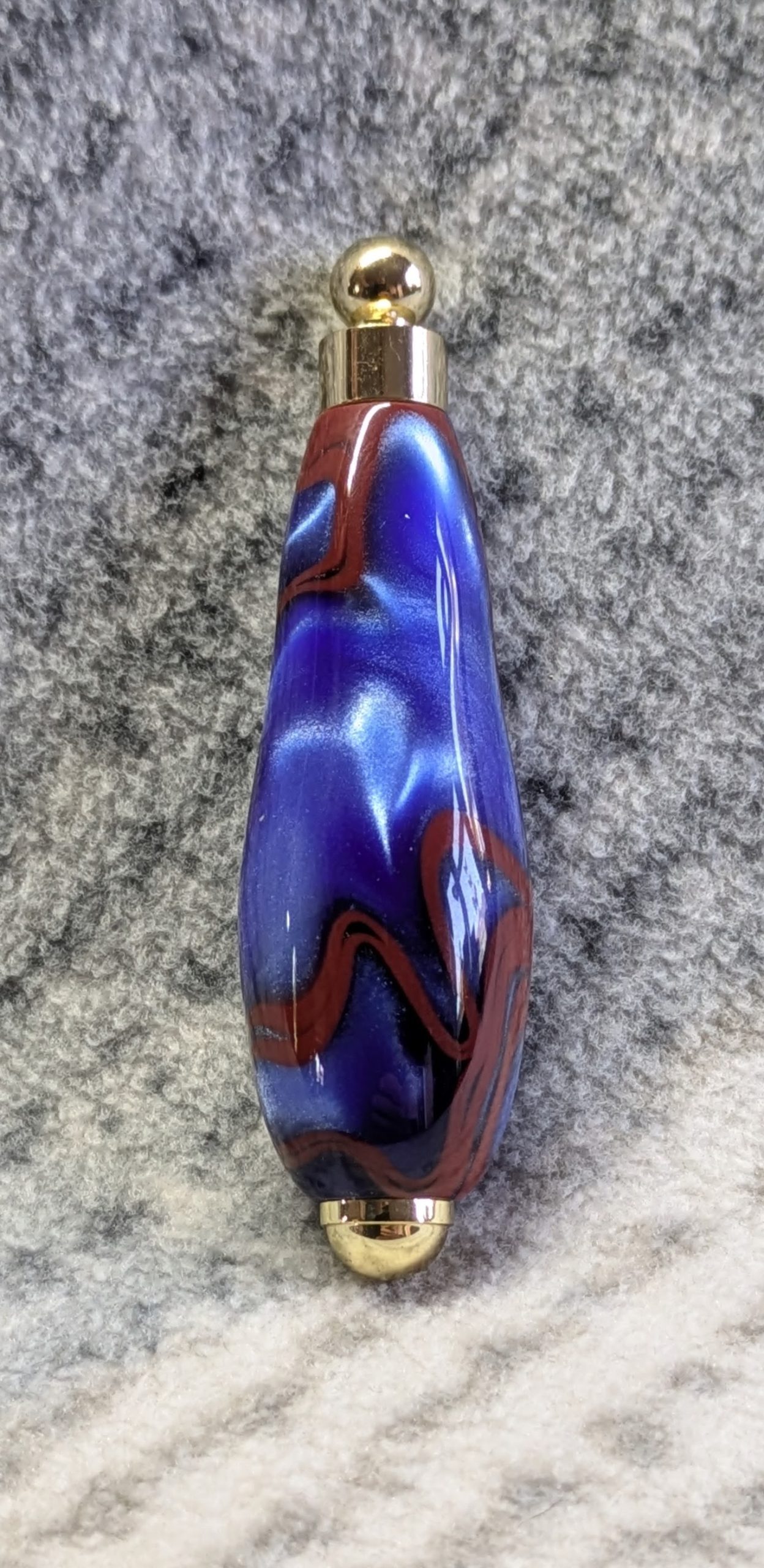 Light switch pull pendant made from blue acrylic with red swirls and gold coloured fittings