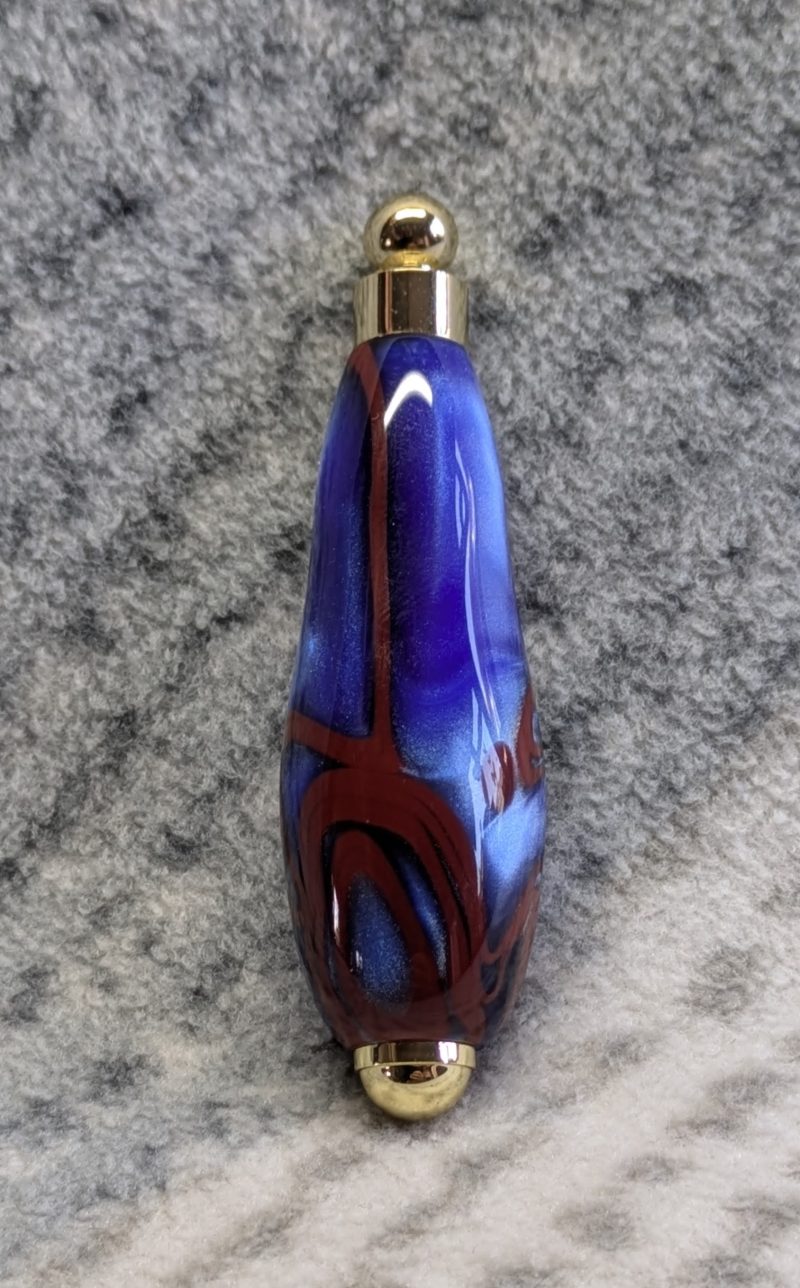 Light switch pull pendant made from blue acrylic with red swirls and gold coloured fittings