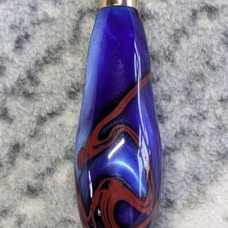 Light switch pull pendant made from blue acrylic with red swirls and gold coloured fittings