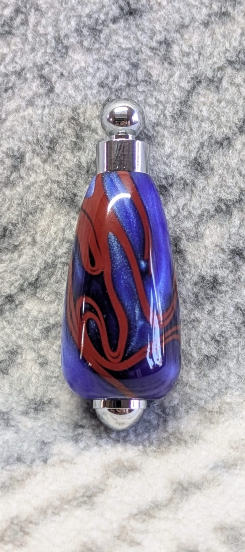 Light switch pull pendant made from blue acrylic with red swirls and chrome fittings