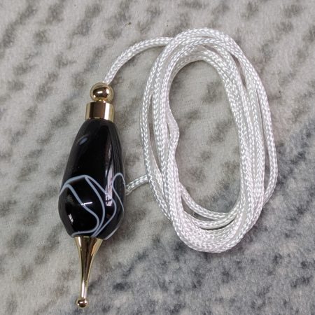 Light switch pull pendant made from black acrylic with white swirls and gold coloured fittings