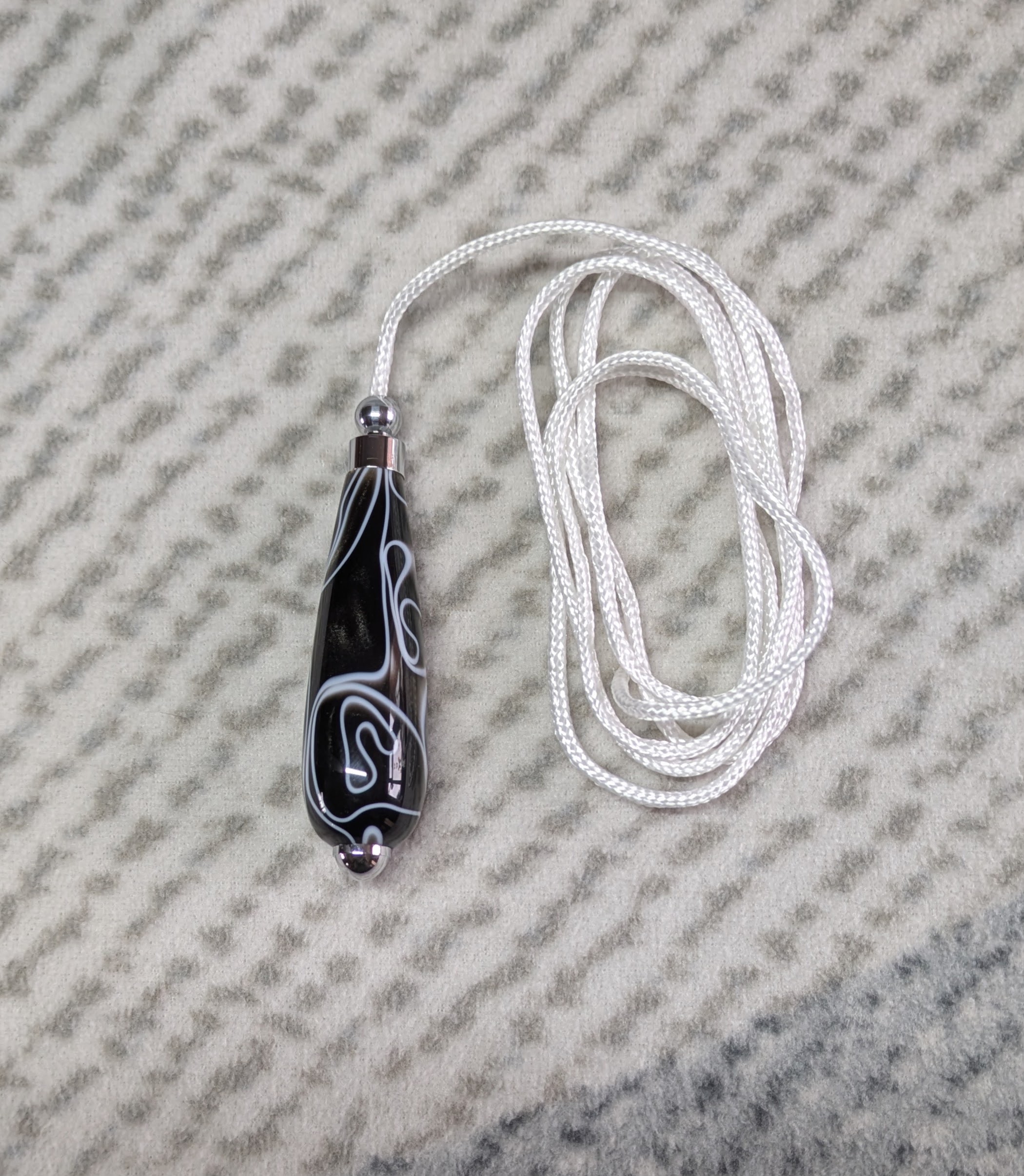 Light switch pull pendant made from black acrylic with white swirls and chrome fittings