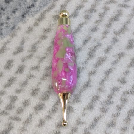 Light switch pull pendant made from pink acrylic with pale green pieces and gold coloured fittings