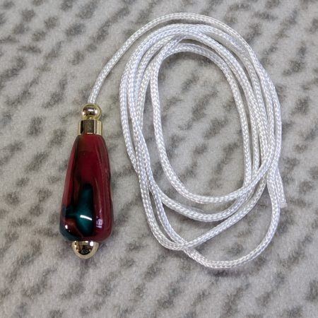 Light switch pull pendant made from red, green and gold acrylic with gold coloured fittings