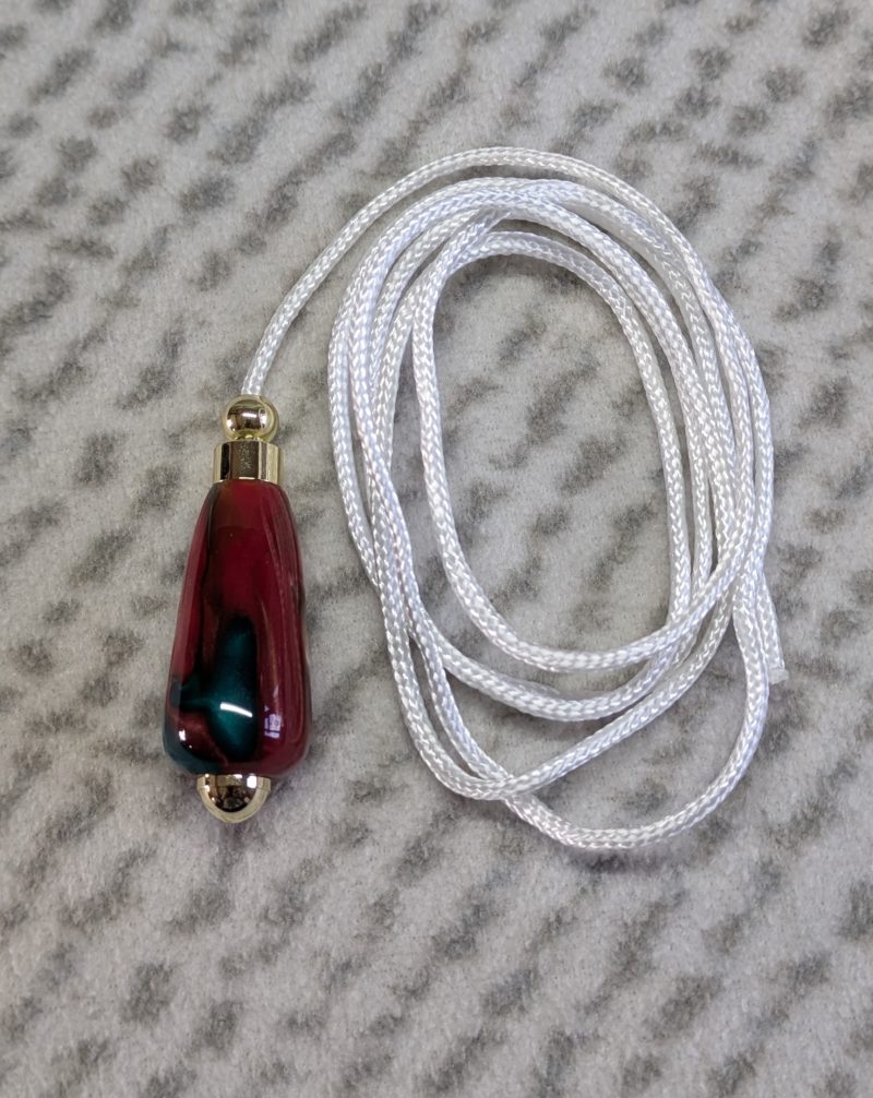 Light switch pull pendant made from red, green and gold acrylic with gold coloured fittings