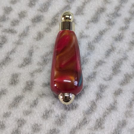 Light switch pull pendant made from red, green and gold acrylic with gold coloured fittings