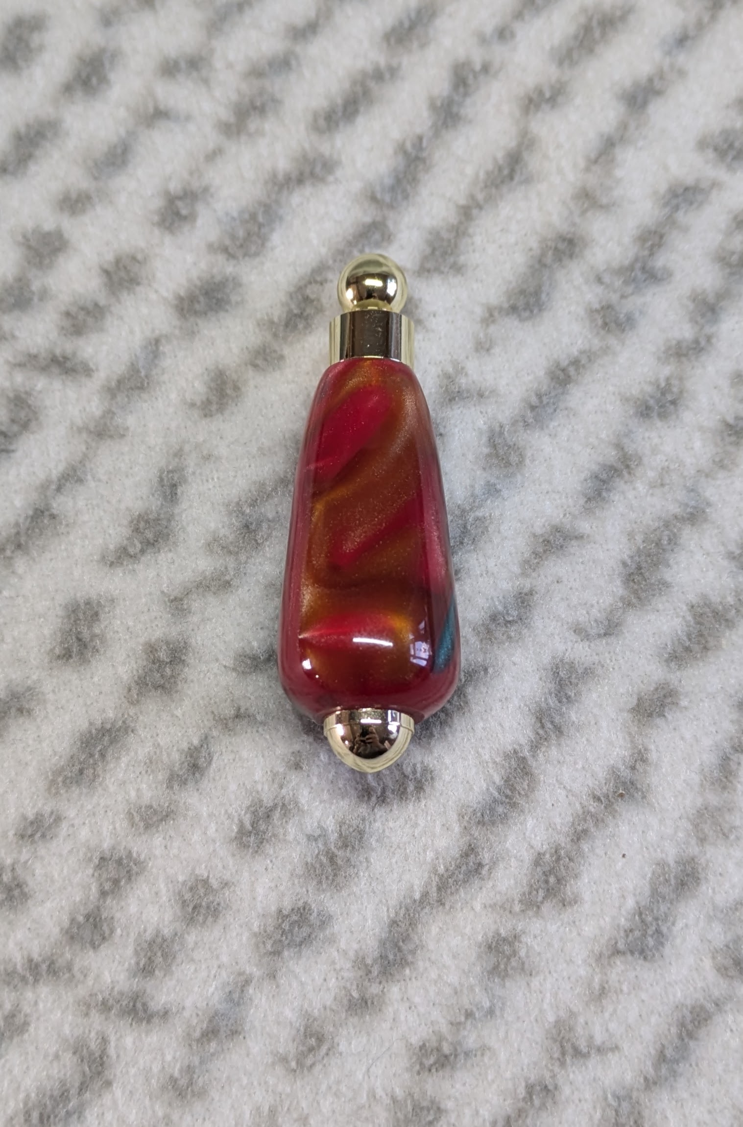 Light switch pull pendant made from red, green and gold acrylic with gold coloured fittings