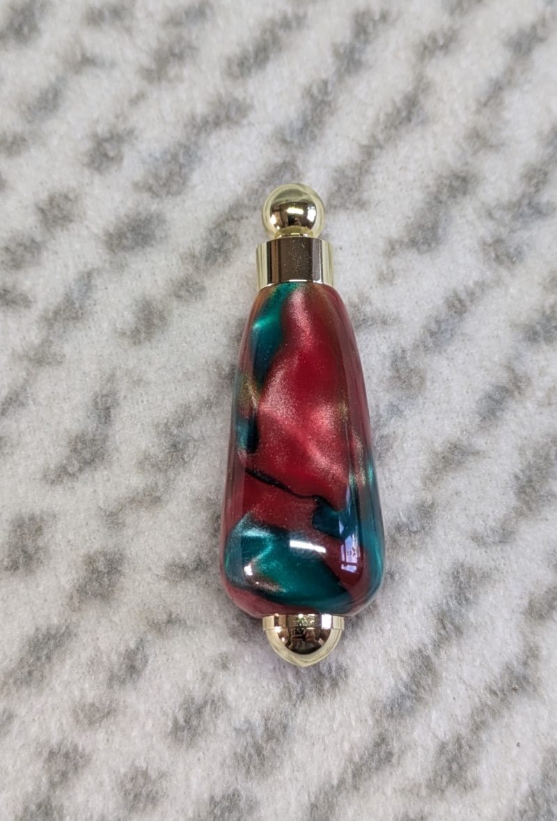 Light switch pull pendant made from red, green and gold acrylic with gold coloured fittings