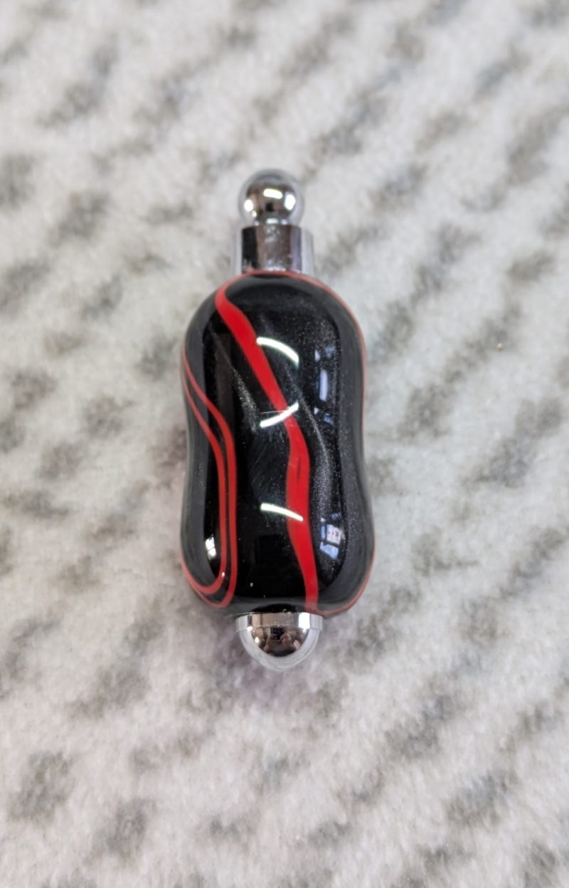 Light switch pull pendant made from shimmering black acrylic with red lines and chrome fittings