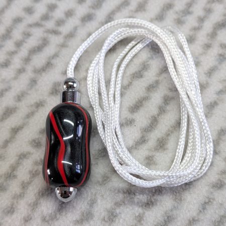 Light switch pull pendant made from shimmering black acrylic with red lines and chrome fittings