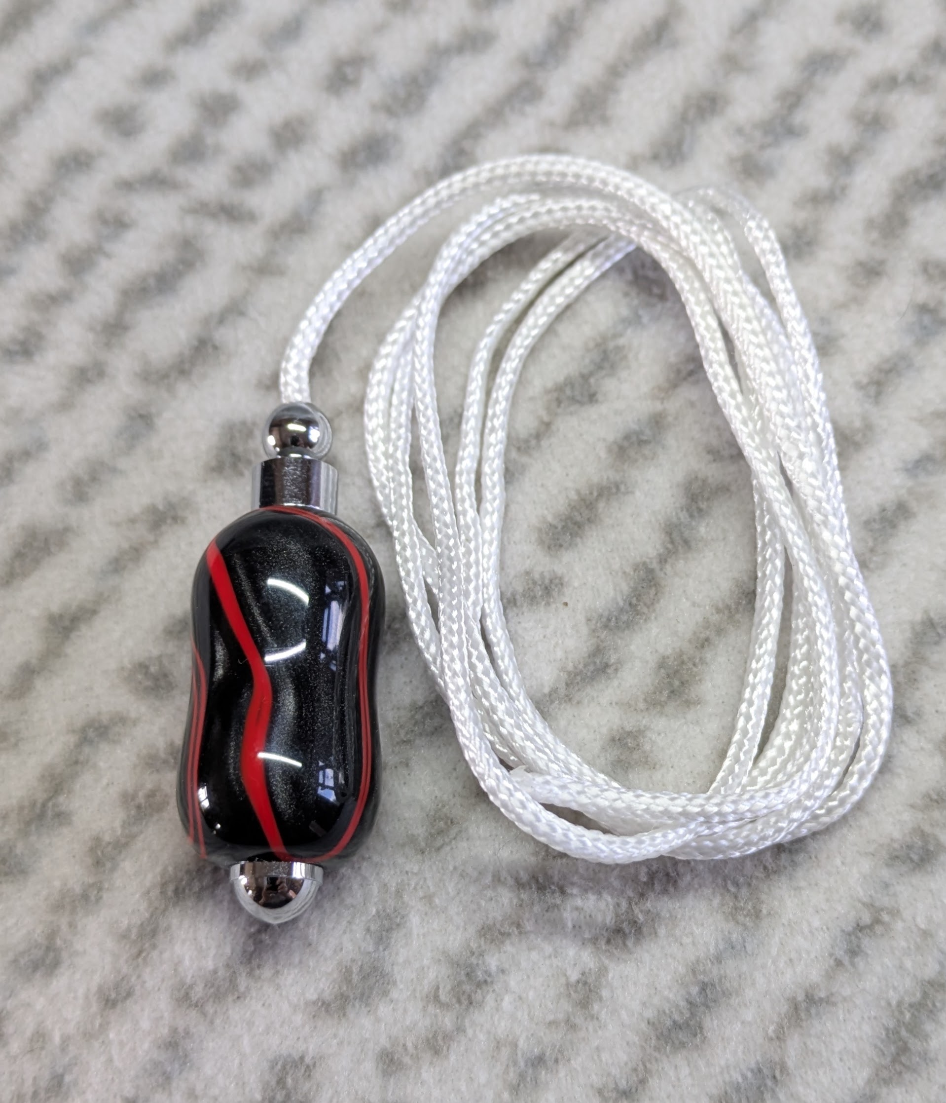 Light switch pull pendant made from shimmering black acrylic with red lines and chrome fittings